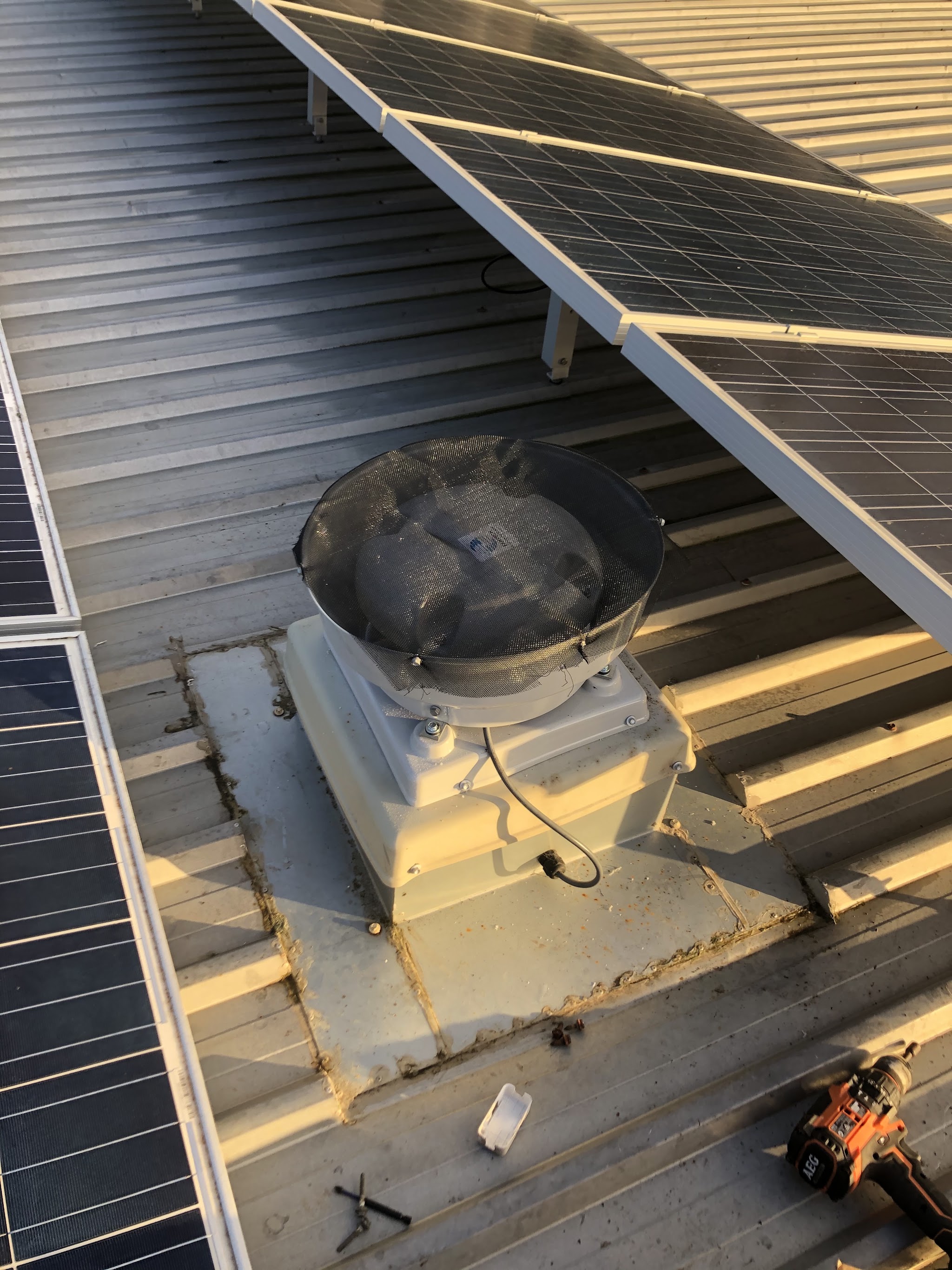 A roof ventilation fan newly installed and flashed into a colorbond roof between two rows of solar panels
